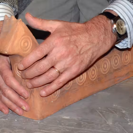 Examen tactile d'une poterie en forme d'animal